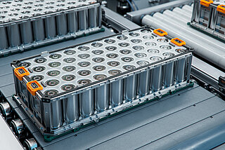 One of the stages in battery module production: conveyor belt with battery packs being transported.