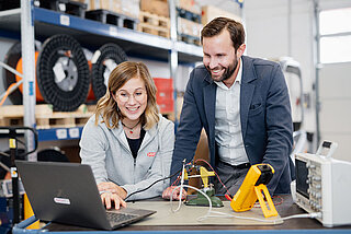 HYDAC system expertise shows a female employee and male employee taking measurements on various devices.